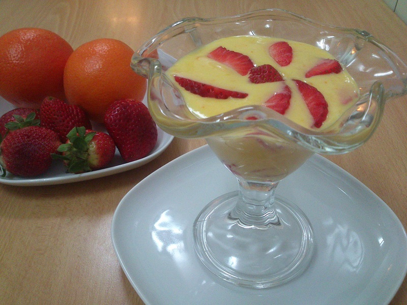 Copa de crema de naranjas decorada con fresas