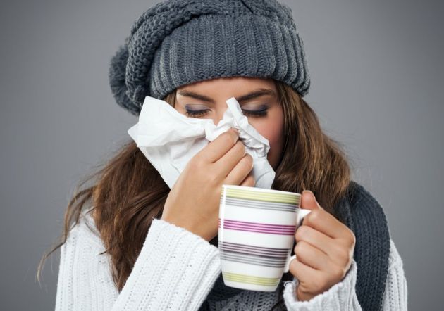 Mujer resfriada con infusión y pañuelo