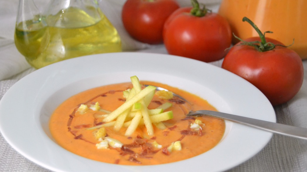Plato blanco con slamrejo de manzana y de fondo tomates y aceitera