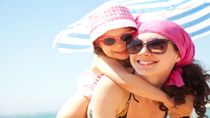 Madre e hija con gafas de sol en la playa