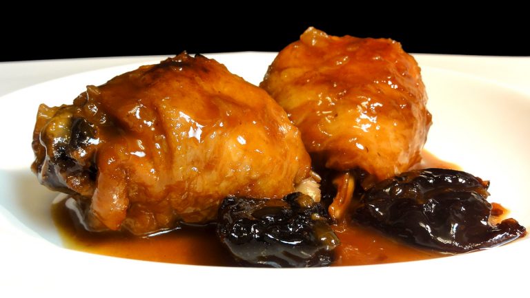 Muslos de pollo con salsa de vino dulce y pasas en un plato blanco