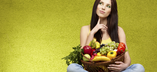 Mujer pensativa con cesta de frutas en la mano sobre fondo verde