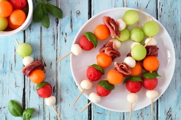 Plato blanco con brochetas de frutas de verano y mozzarella