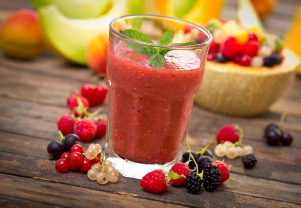 Batido de fresas y moras en vaso de cristal sobre mesa de madera