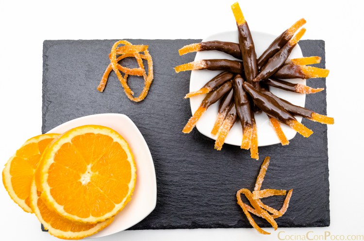 Base de pizarra y encima platos blancos uno con naranja laminaday otro con piel de naranja con chocolate