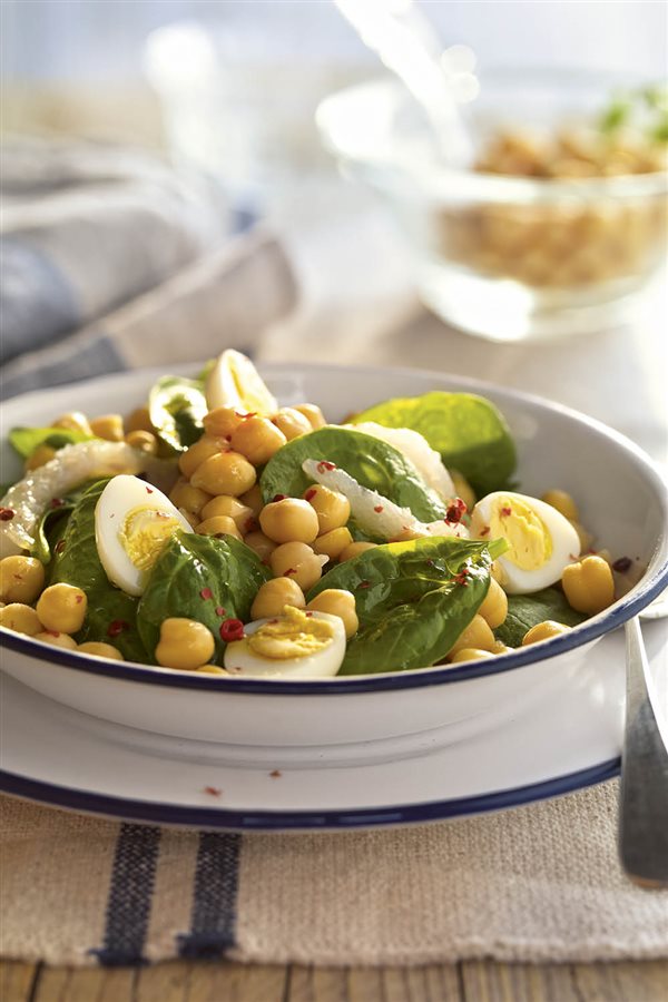 Bol blanco con ensalada de espinacas, bacalao y garbanzos