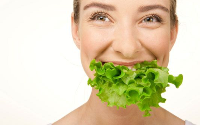 Mujer riendose y comiendo lechuga
