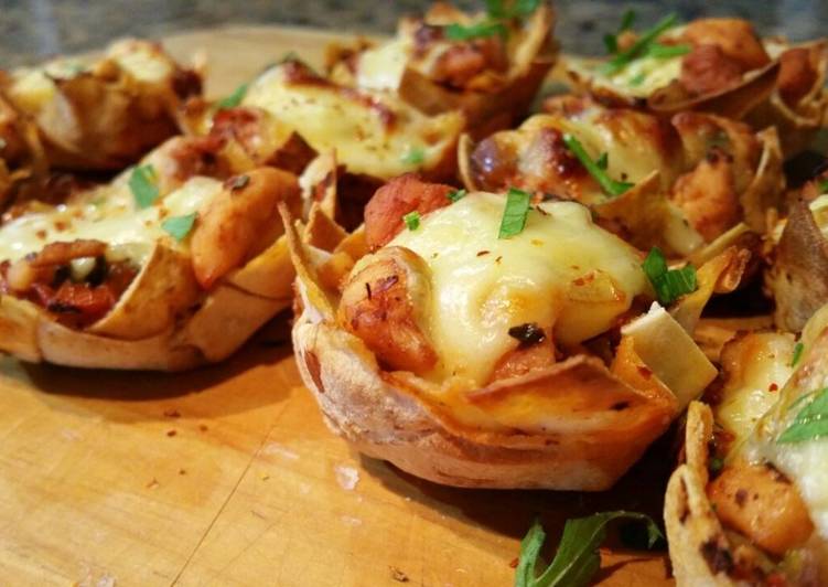 Tartaletas de pollo, queso y tomate sobre tabla de madera