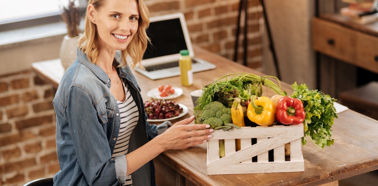Mujer en casa encima mesa de madera con frutas y verduras en caja de madera
