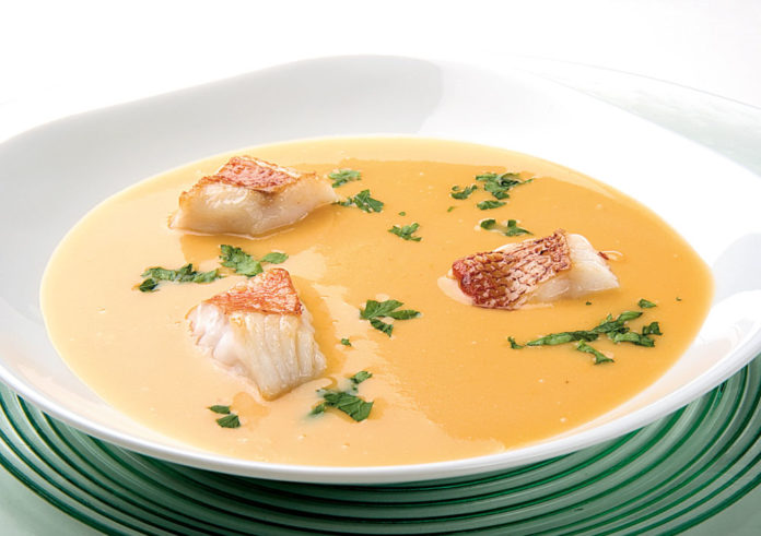 Plato blanco sobre salvamantel verde con crema de cabracho