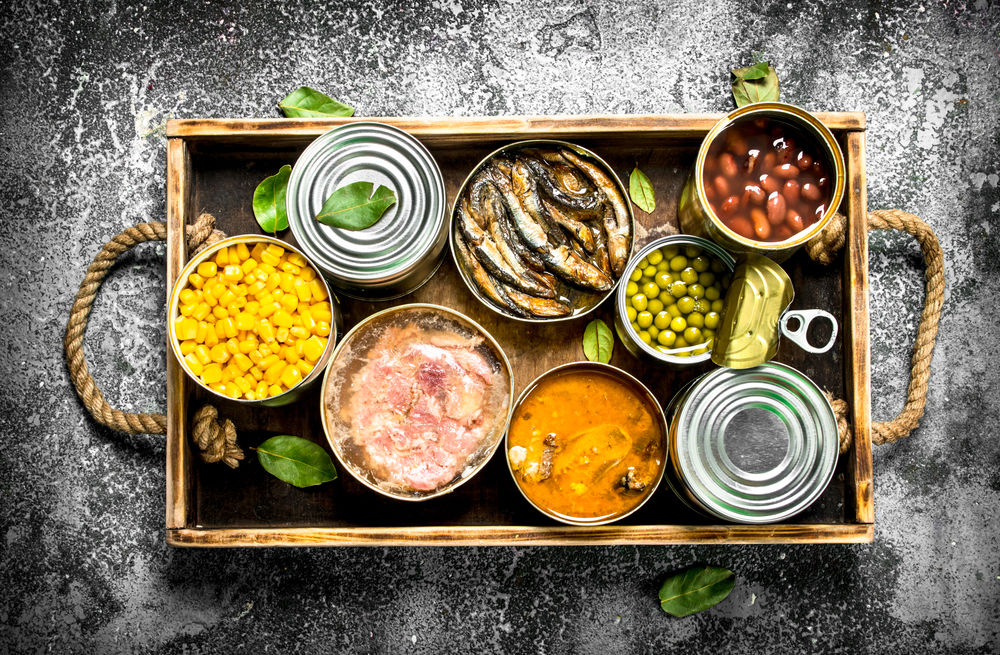 Fondo de pizarra con caja de madera y sobre ella conservas de alimentos