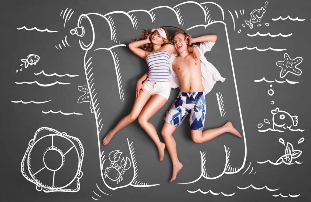 Pareja tumbada sobre dibujo en pizarra de colchoneta de playa