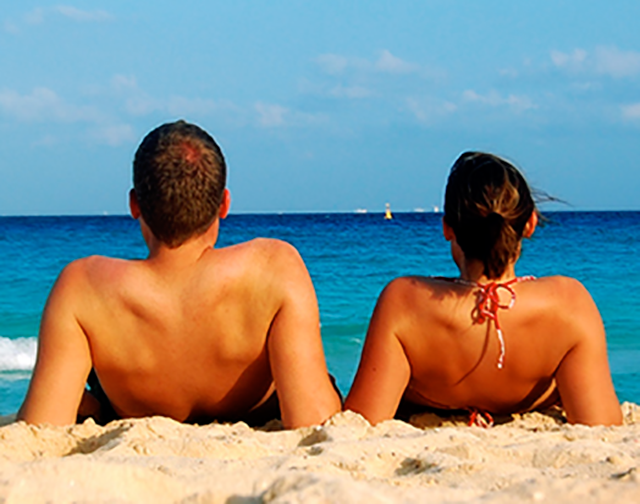 Chico y chica en la playa tomando el sol