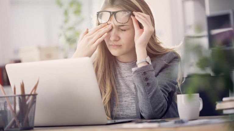 Mujer frontándose los ojos delante de un odenador