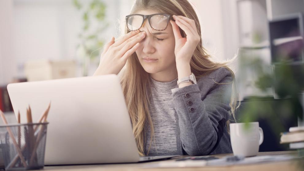 Mujer frontándose los ojos delante de un odenador