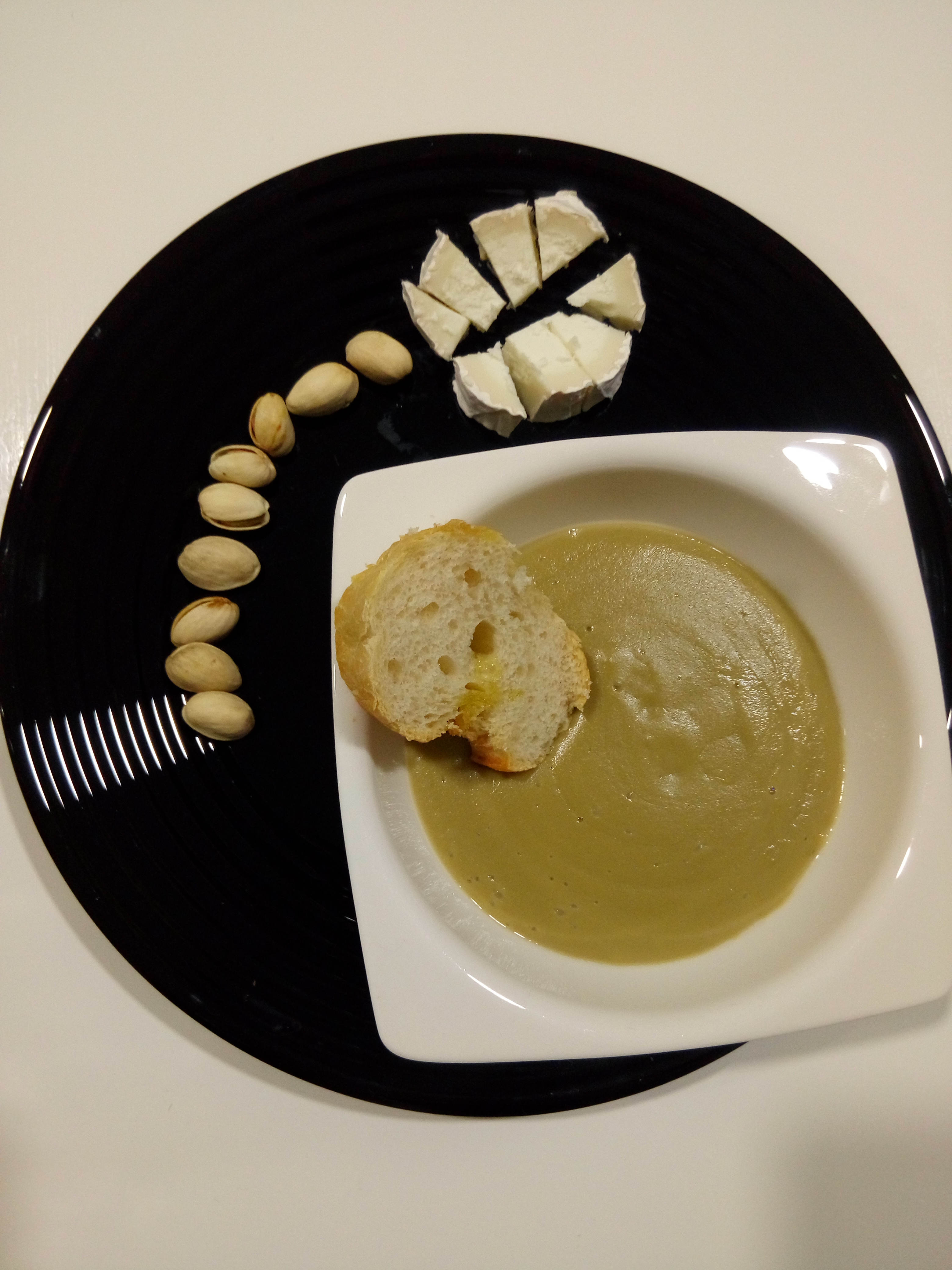 Plato negro con crema de alcachofas y pistachos