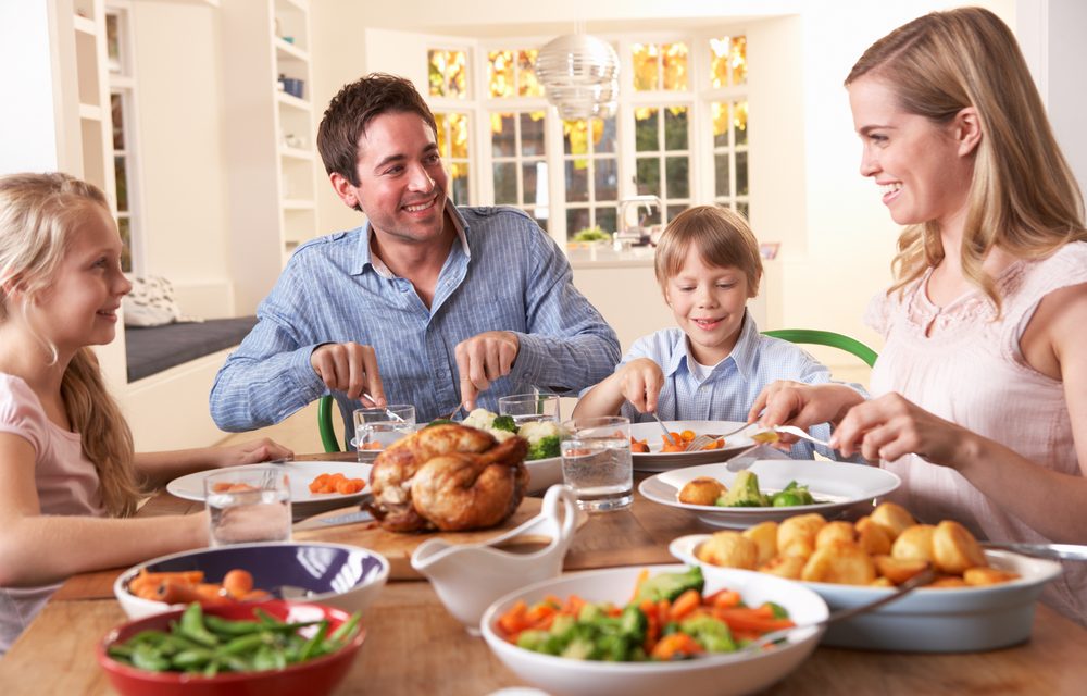 Familia comiendo feliz sobre mesa de madera