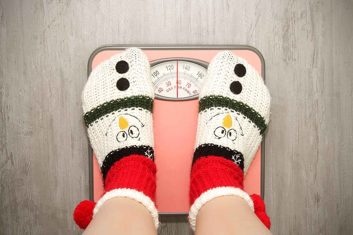 Mujer con calcetines navideños sobre báscula