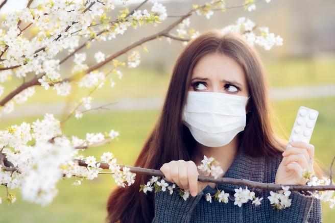 Mujer con mascarilla mriando de reojo a un árbol que le provoca alergia