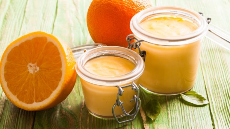 Vasos de cristal con crema de naranja y naranjas alrededor