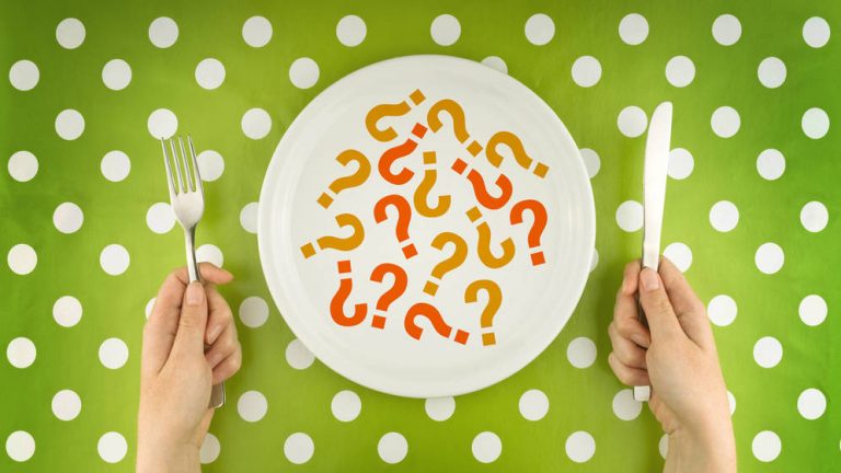 Plato blanco con interrogaciones y persona que piensa que comer