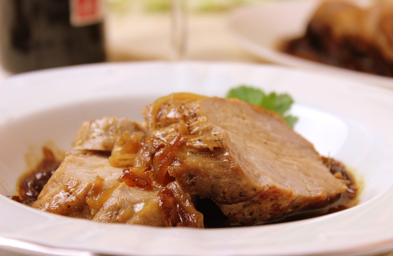 Plato blanco con solomillo de cerdo con cebolla confitada