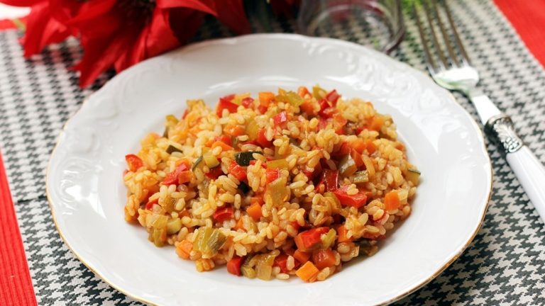 Arroz integral con calabaza , puerro y pimientos en plato blanco
