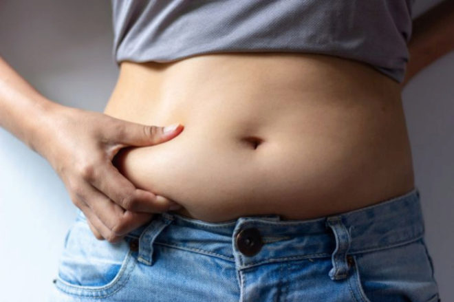 Mujer con vaqueros tocándose la barriga