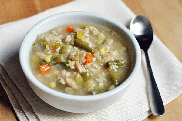 Plato de sopa de verduras con arroz y una cuchara