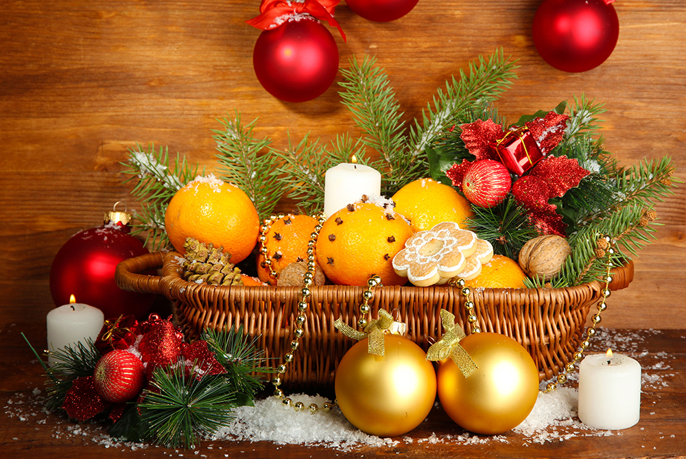 Cesta de madera con naranjas y adornos navideños