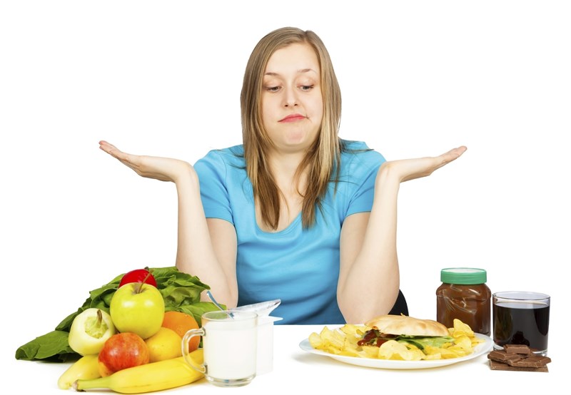 Mujer con diferentes alimentos y dudas sobre que comer