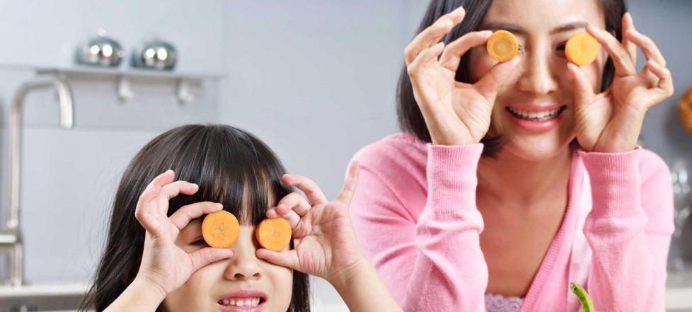 Madre e hija con rodajas de zanahoria en los ojos