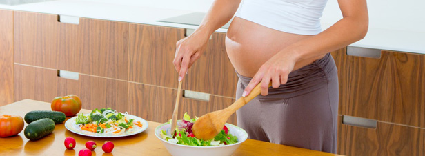 Mujer embaraza en la cocina preparando comida