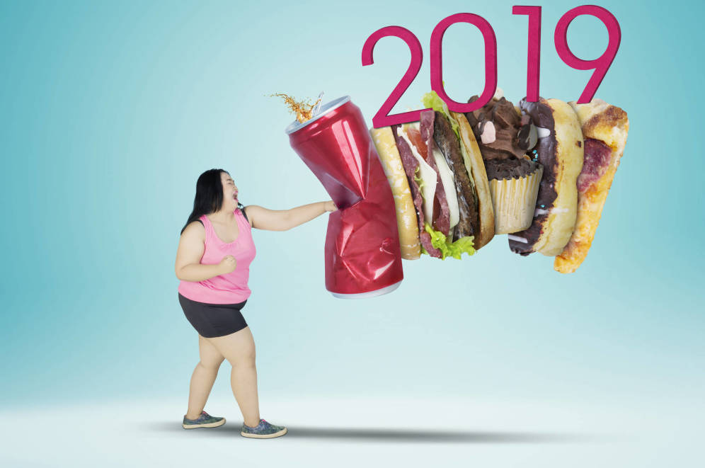 Mujer dando un golpe a la comida basura y de fondo se lee 2019