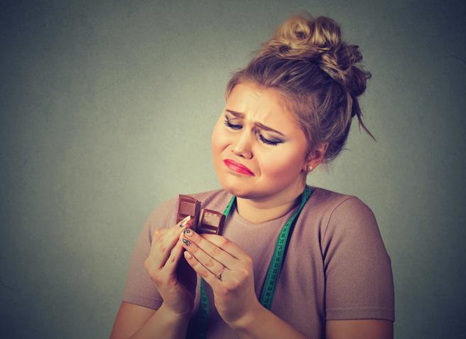 Mujer que con tristeza mira una onza de chocolate