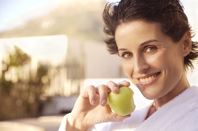 Mujer madura sonriendo con manzana en la mano