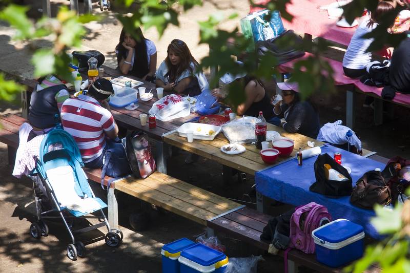 Familia reunida en un banco al aire libre comiendo