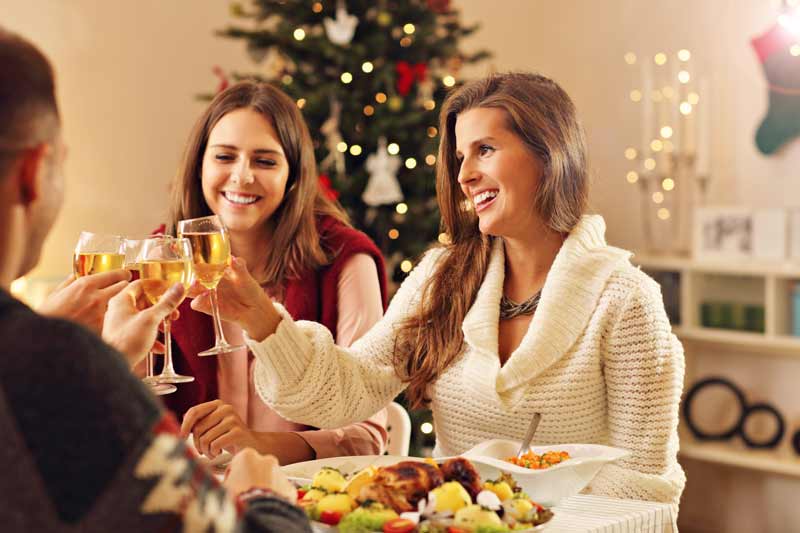 Mujeres brindando y comiendo en mesa de navidad