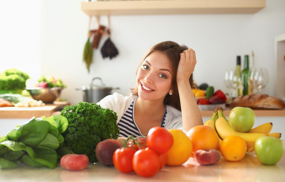 Mujer frente a mesa de la cocina con alimentos saludables