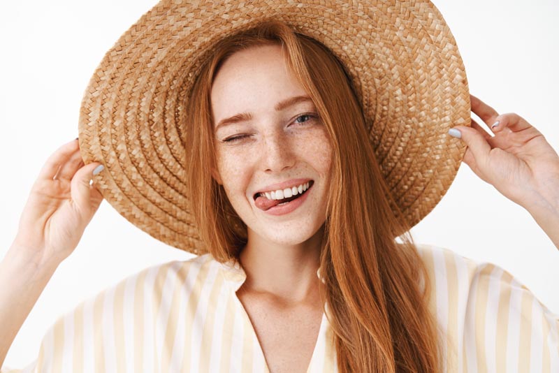 Mujer sonriendo y guiñamndo un ojo con un sombrero